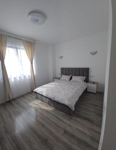 a white bedroom with a large bed and wooden floors at Vera Home 3 in Râmnicu Vâlcea