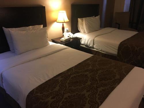 a hotel room with two beds and a lamp at Shepherd Hotel in Amman