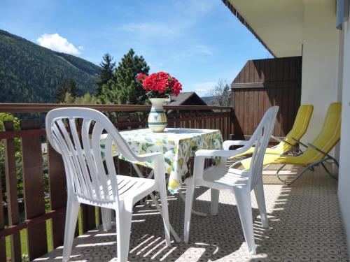 a table and chairs on a balcony with a vase of flowers at Garni B&B Apartments Plank in Nova Levante