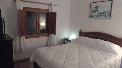 a bedroom with a white bed and a window at EL CHORRO Aire acondicionado Bar privado Barbacoa Amplios patios in Castalla
