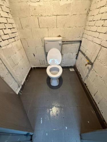 a bathroom with a white toilet in a brick wall at Fresia Villa & Camping in Beranang