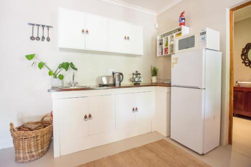 eine Küche mit weißen Schränken und einem weißen Kühlschrank in der Unterkunft Hoogwater Cottage in Wolseley