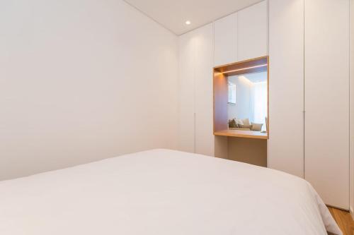 a white bedroom with a bed and a mirror at Estoril Palace - A chic getaway in Estoril