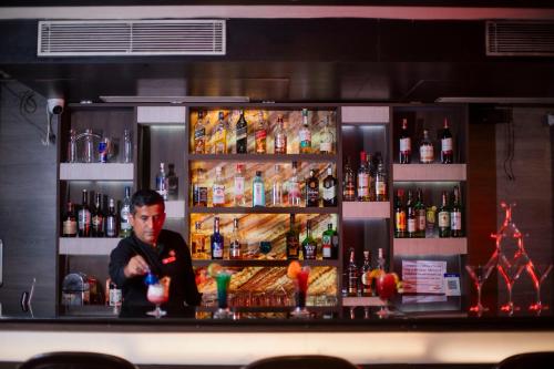 a man standing behind a bar with a drink at Ethnotel, Kolkata Airport in Kolkata