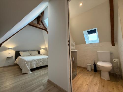 a bedroom with a bed and a toilet in a attic at Étage complet à la campagne in Chanzeaux