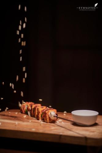 a piece of meat on a cutting board with a bowl at Ethnotel, Kolkata Airport in Kolkata