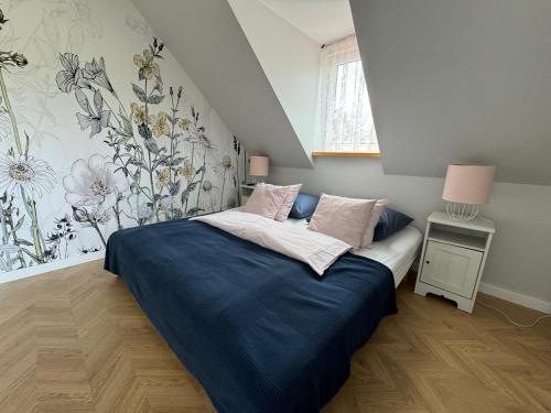 a bedroom with a bed with blue sheets and flowers on the wall at Pokoje Irys in Kazimierz Dolny