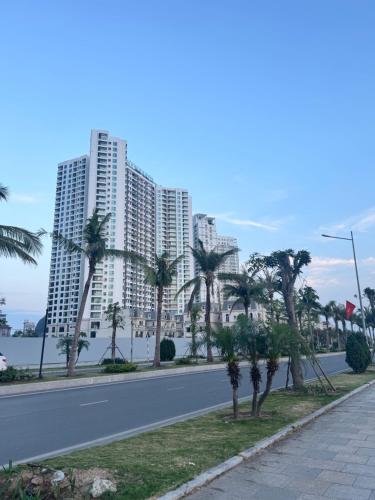 a street with palm trees in front of tall buildings at Lavender House- The Sapphire Resident 2 in Ha Long