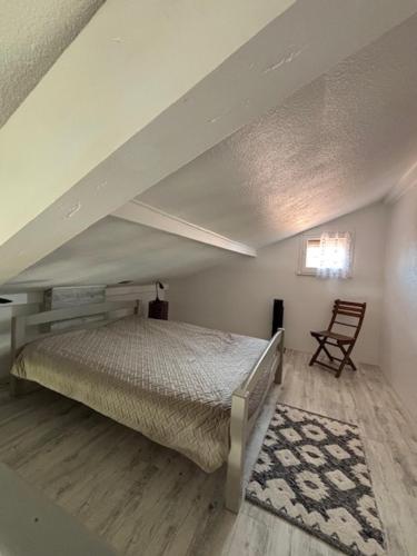 une chambre mansardée avec un lit et une chaise dans l'établissement Les Cottages 1 - Studio au bord de l'océan, à Biscarrosse