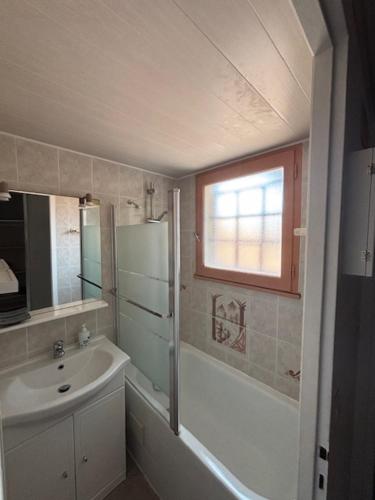 La salle de bains est pourvue d'un lavabo, d'une baignoire et d'une fenêtre. dans l'établissement Les Cottages 1 - Studio au bord de l'océan, à Biscarrosse
