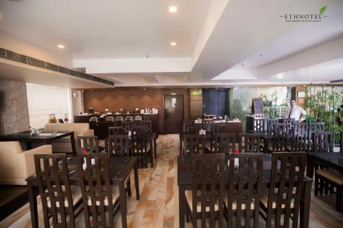 a restaurant with chairs and a man standing in the background at Ethnotel, Kolkata Airport in Kolkata
