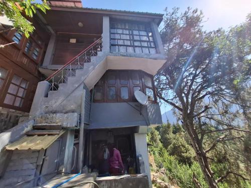 a building with two people standing outside of it at Aasha's Home in Kalpa