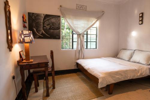 a bedroom with a bed and a table and a window at Kobe Nature Homestay in Arusha