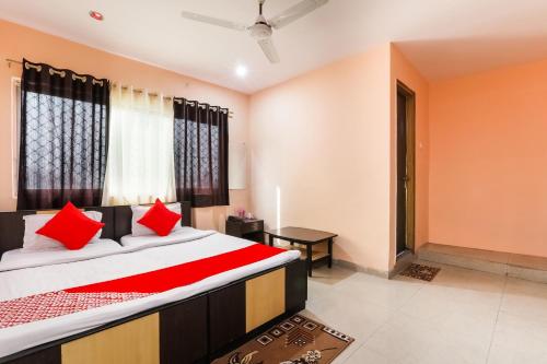 a bedroom with a large bed with red pillows at Hotel O Priyal in Chās