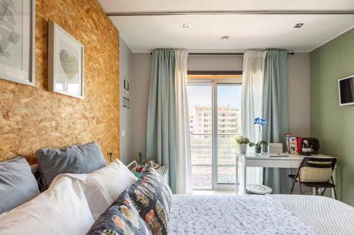 a bedroom with a bed and a desk and a window at SunHouse Room in Albufeira