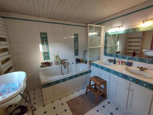 une salle de bain avec deux lavabos, une baignoire et un miroir dans l'établissement Delighting young and old alike, à Saint-Quentin-la-Poterie