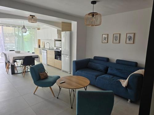 un salon avec un canapé bleu et une table dans l'établissement Maison avec extérieur à 150 mètres de la plage - 4 chambres climatisées, à Saint Cyprien Plage