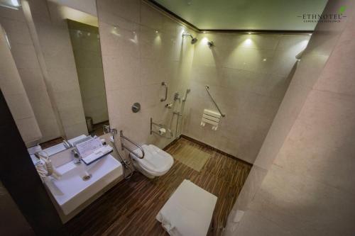 a bathroom with a toilet and a sink at Ethnotel, Kolkata Airport in Kolkata