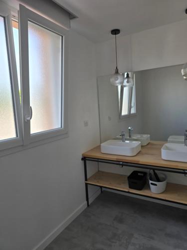 une salle de bain avec deux lavabos et une fenêtre dans l'établissement Maison avec extérieur à 150 mètres de la plage - 4 chambres climatisées, à Saint Cyprien Plage