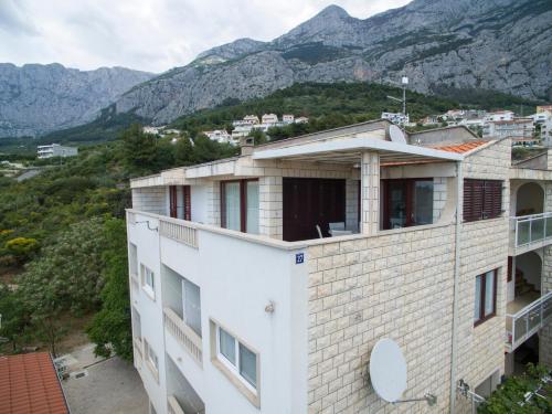 a view of a building with mountains in the background at Villa Makarana Apartments in Makarska