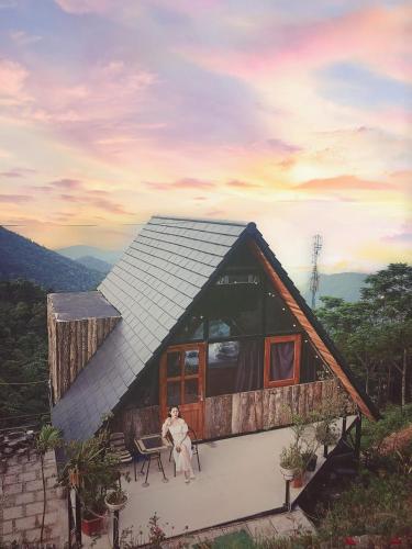 a woman is sitting in front of a house at An House, Farm & Trekking in Tam Ðảo