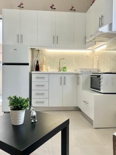 a kitchen with white cabinets and a table with a plant at Aiginetan Apartments in Aegina Town