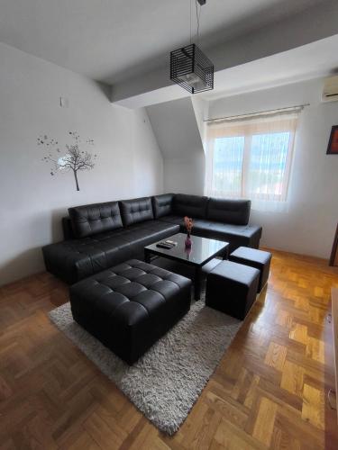 a living room with a black leather couch and a table at D Center Apartment in Kumanovo