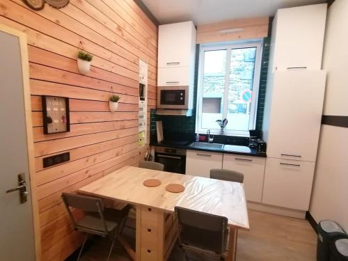 - une cuisine avec un mur en bois, une table et des chaises dans l'établissement Petit cocon centre MONT DORE, à Le Mont-Dore