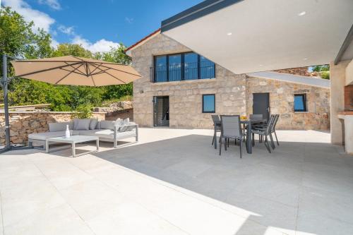 a patio with a table and chairs and an umbrella at Hideaway Stonehouse pool for 2 Dalmatia Imotski in Medvidovići