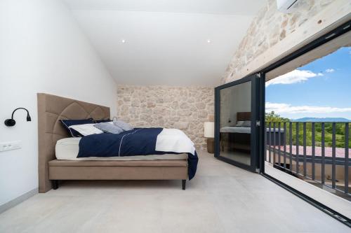 a bedroom with a bed and a large window at Hideaway Stonehouse pool for 2 Dalmatia Imotski in Medvidovići