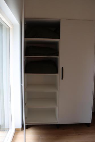 a closet with white shelves and a door at cozy cube 1 Luxury Apartments, nah an der Messe, 30 Minuten zu den Bergen und Seen, 20 Minuten nach München in Glonn