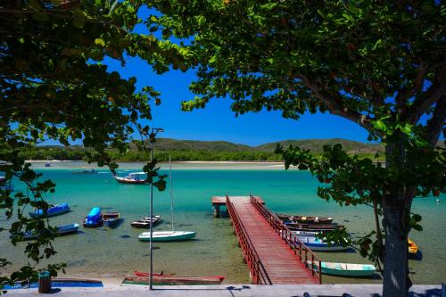 a dock with boats in the water on a beach at Hotel Solar do Arco in Cabo Frio