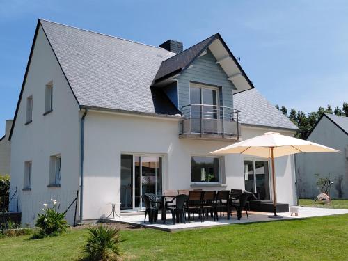 a white house with a table and an umbrella at Maison du Mont César in Montchaton