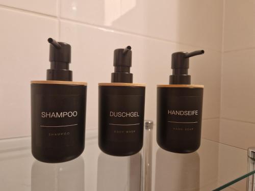 three bottles of shampoos on a glass shelf in a bathroom at Sunshine Beach House, DIREKT AM SEE, eigenes BOOT, PRIVATE BEACH, Grill, WLAN in Szántód