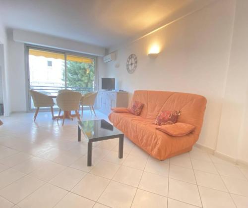 un salon avec un canapé orange et une table dans l'établissement Cannes proche Croisette - Studio balcon vue sur jardin, à Cannes