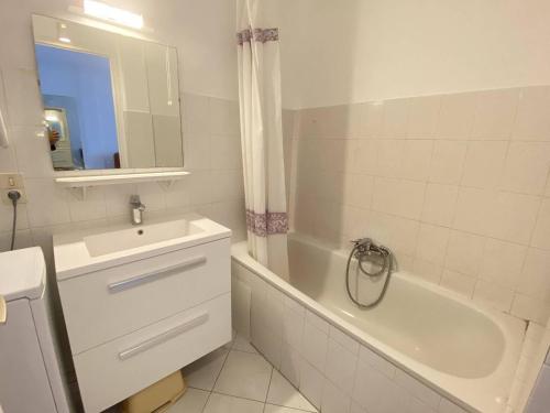 La salle de bains est pourvue d'un lavabo, d'une baignoire, d'un lavabo et d'un miroir. dans l'établissement Cannes proche Croisette - Studio balcon vue sur jardin, à Cannes