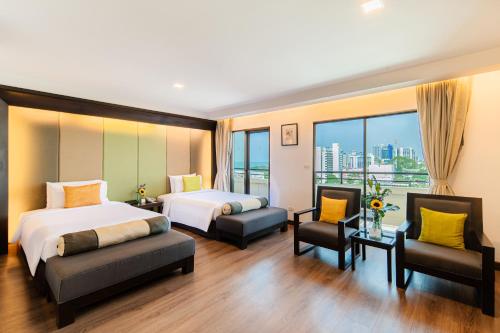 a hotel room with two beds and two chairs at Sunbeam Hotel Pattaya in Pattaya Central
