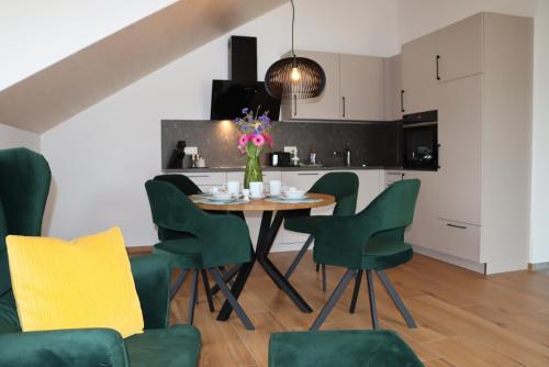 a kitchen and dining room with a table and green chairs at cozy cube 1 Luxury Apartments, nah an der Messe, 30 Minuten zu den Bergen und Seen, 20 Minuten nach München in Glonn