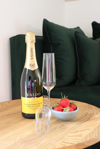 a bottle of wine and a bowl of strawberries on a table at cozy cube 1 Luxury Apartments, nah an der Messe, 30 Minuten zu den Bergen und Seen, 20 Minuten nach München in Glonn