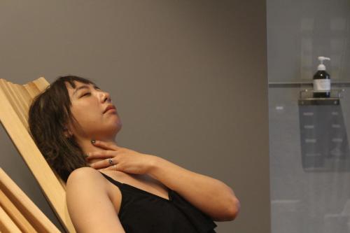 a woman sitting in a chair looking in a mirror at UNPLAN Residence suite in Chikuni