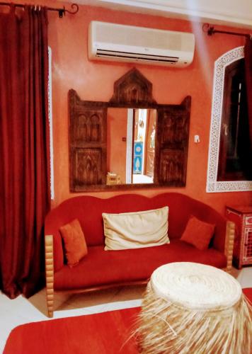 a living room with a red couch and a mirror at maison d'hôtes Le petit jardin Marrakech in Marrakech