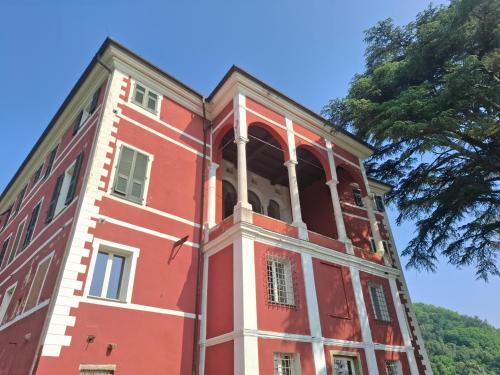 a red and white building with a tree at Albergo Palazzo Costa in Beverino