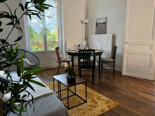 un salon avec une table et des chaises et une fenêtre dans l'établissement Cozy appartement 2 chambres au coeur de Palaiseau 8min RER B à pieds, à Palaiseau