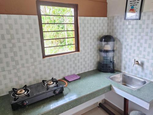 a kitchen counter with a stove and a sink at Greenwood Cabins Maroon House in Jorhat