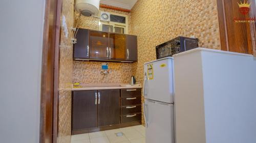 a kitchen with a white refrigerator and brown cabinets at شقق الماسة التاج للوحدات السكنية in Hail