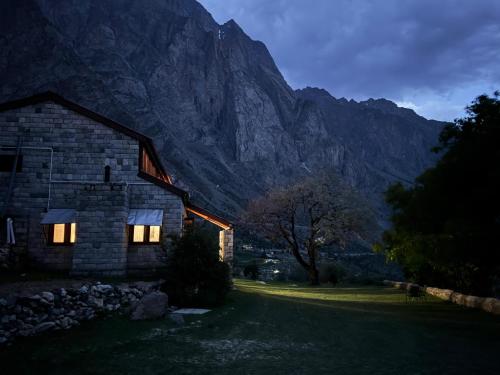 a house with lights on in front of a mountain at The Walnut Tree Lodge, Naltar in Jugut