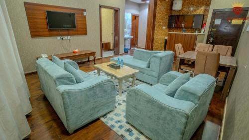 a living room with blue chairs and a table at شقق الماسة التاج للوحدات السكنية in Hail