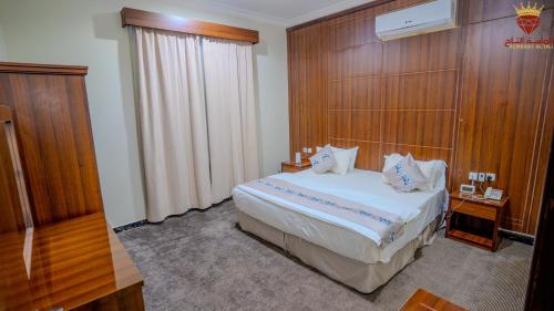 a bedroom with a king sized bed with a wooden wall at شقق الماسة التاج للوحدات السكنية in Hail