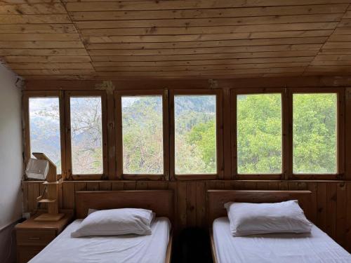 two beds in a room with windows at The Walnut Tree Lodge, Naltar in Jugut
