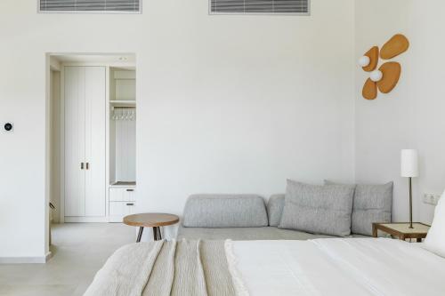 a white room with a bed and a couch at Minnŏ Boutique Hotel & Spa in Skopelos Town